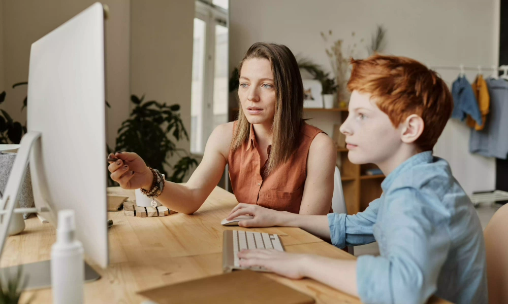 Woman explains kid something at computer