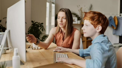 Woman explains kid something at computer