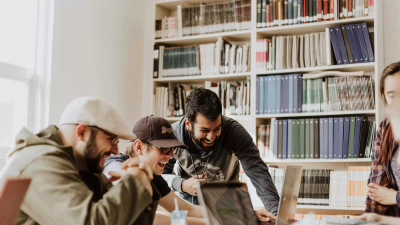Drie mensen die in de bibliotheek op een computer kijken